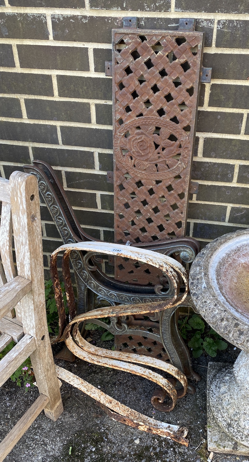 A pair of cast metal bench ends with lattice back (disassembled / no slats) and a pair of wrought iron bench ends